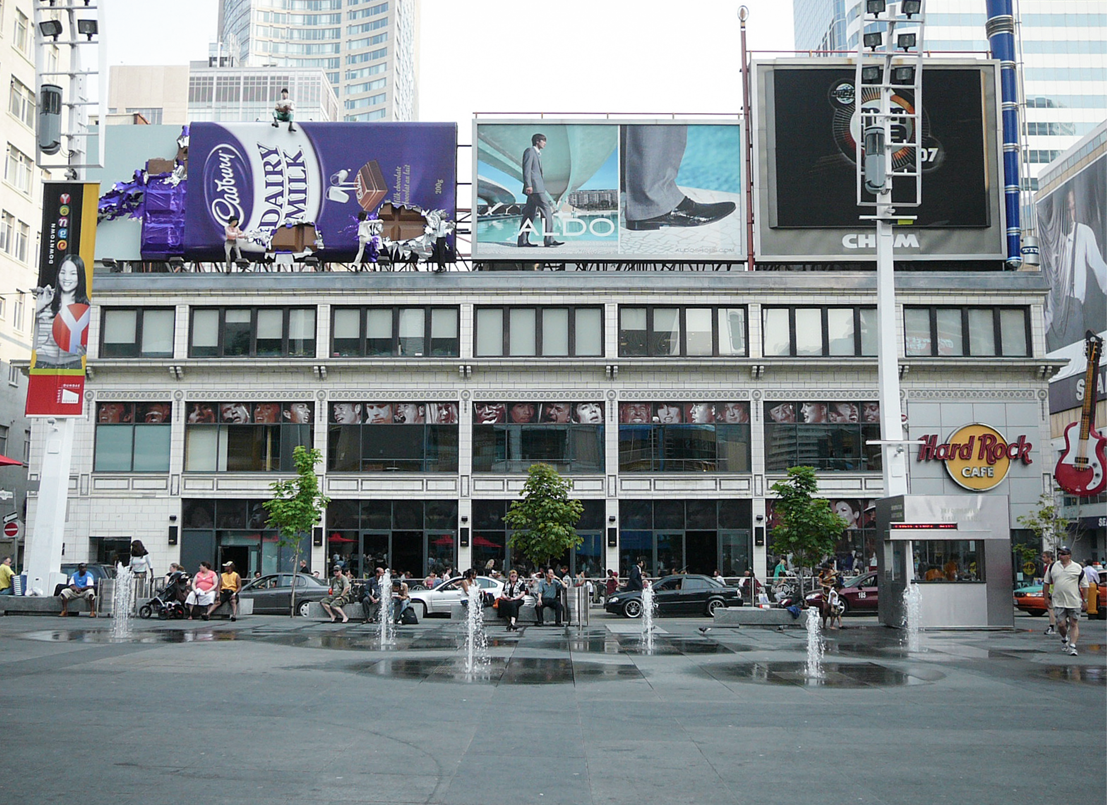 Elevation along Dundas of former Hard Rock Cafe with advertiseents on the roof, and LED signs on the right hand side. High rise towers in the background. 