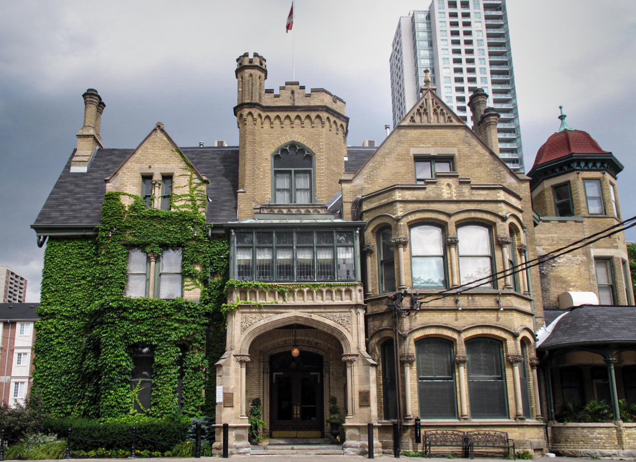 Massey House elevation image, a three storey building with beige brick, stone detailing, bay windows, turrets, and ivey growth