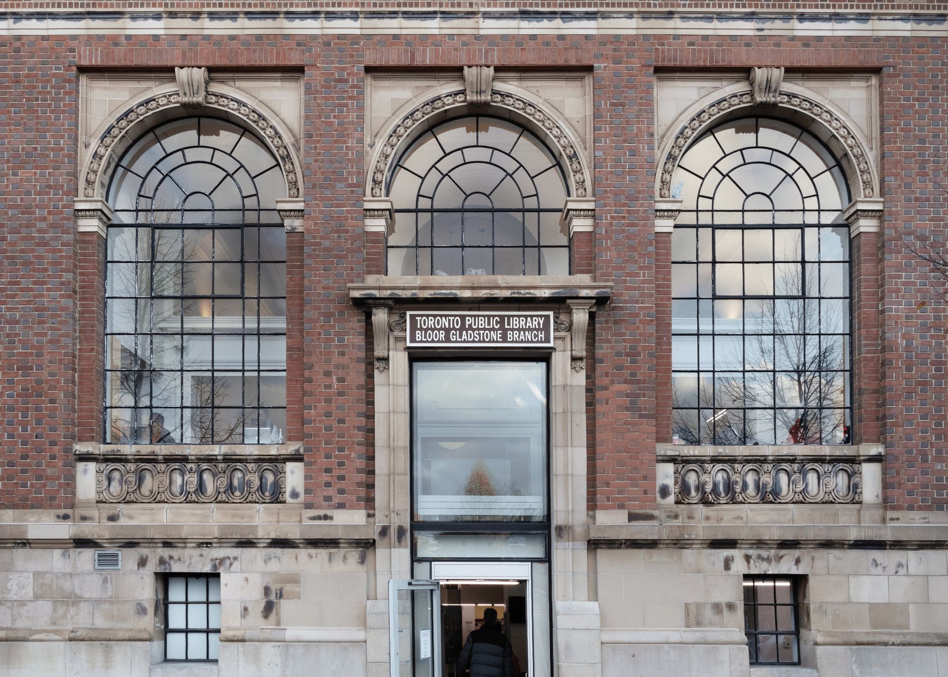 Three windows arch above the door. The sign above the door reads "Toronto Public Library Bloor Gladstone Branch".