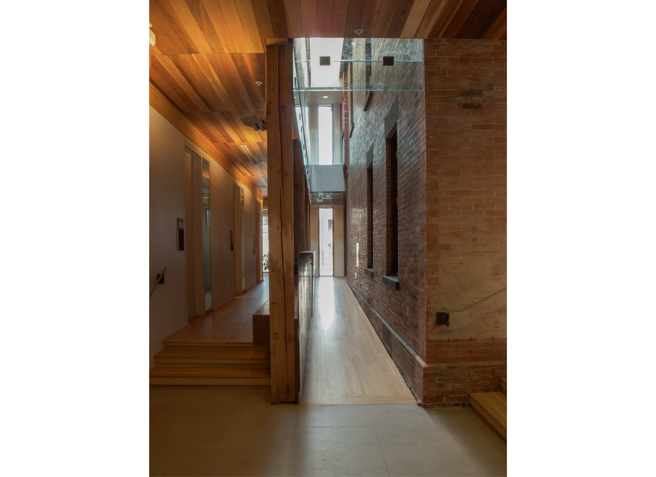 Hallway with red brick wall on the right, and mass timber on the left. 