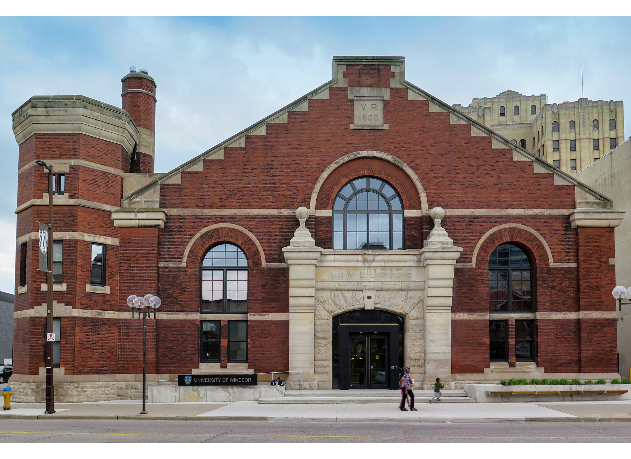 A red brick and stone of Beaux-Arts building with arched windows, a large stone entryway, and small turret to the left.