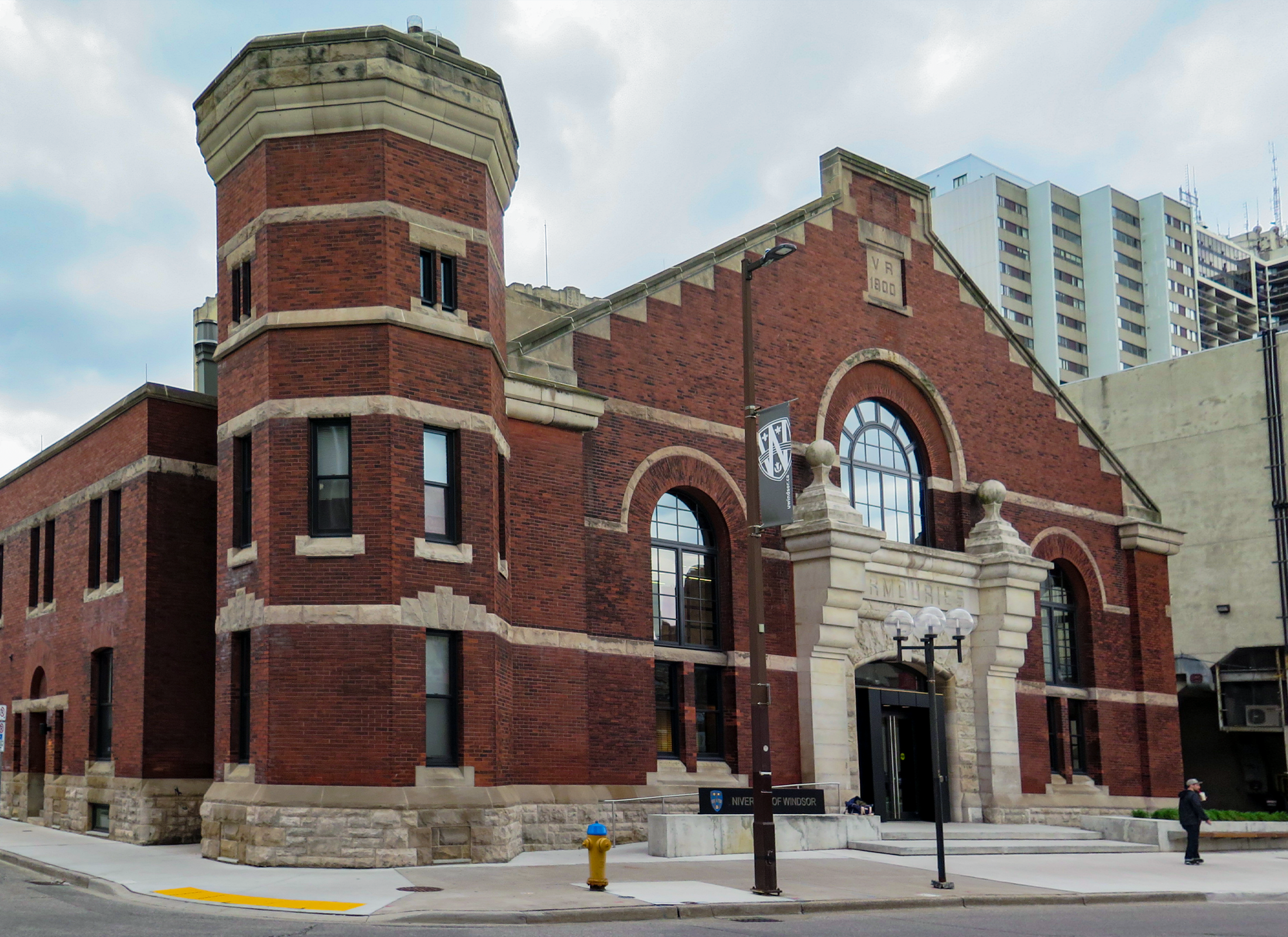 A red brick and stone of Beaux-Arts building with arched windows, a large stone entryway, and small turret to the left.