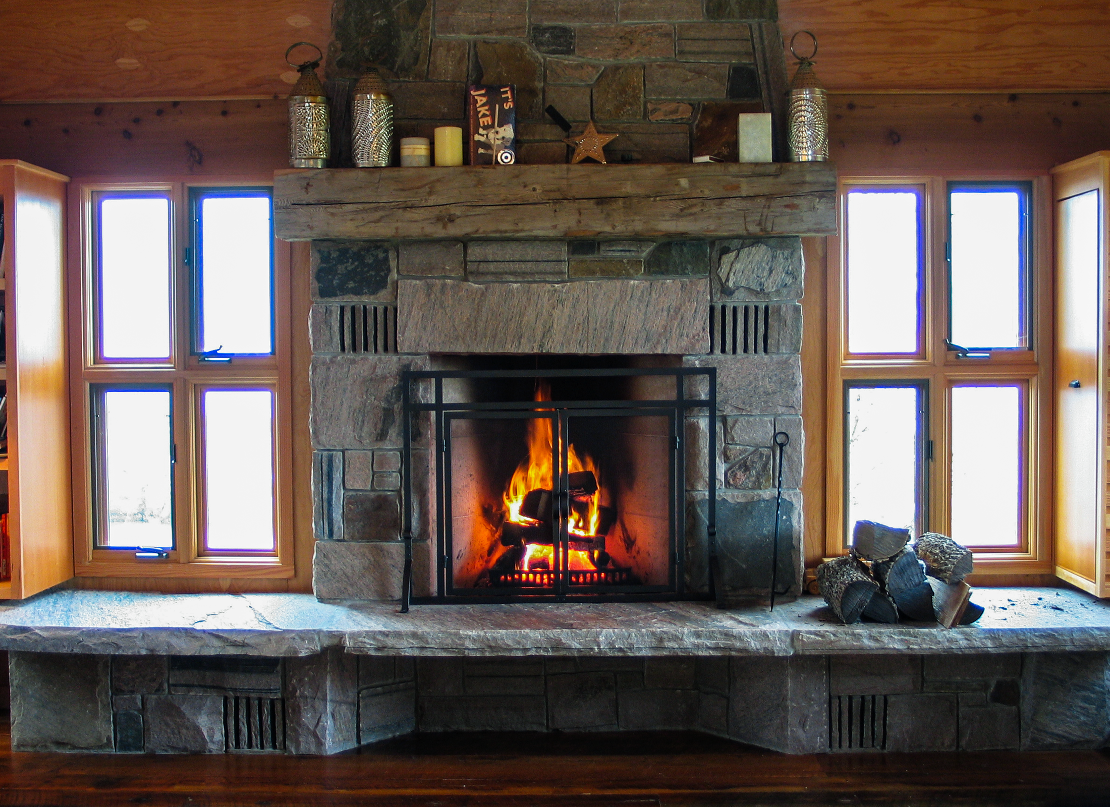 Large stone fireplace sitting between two windows.