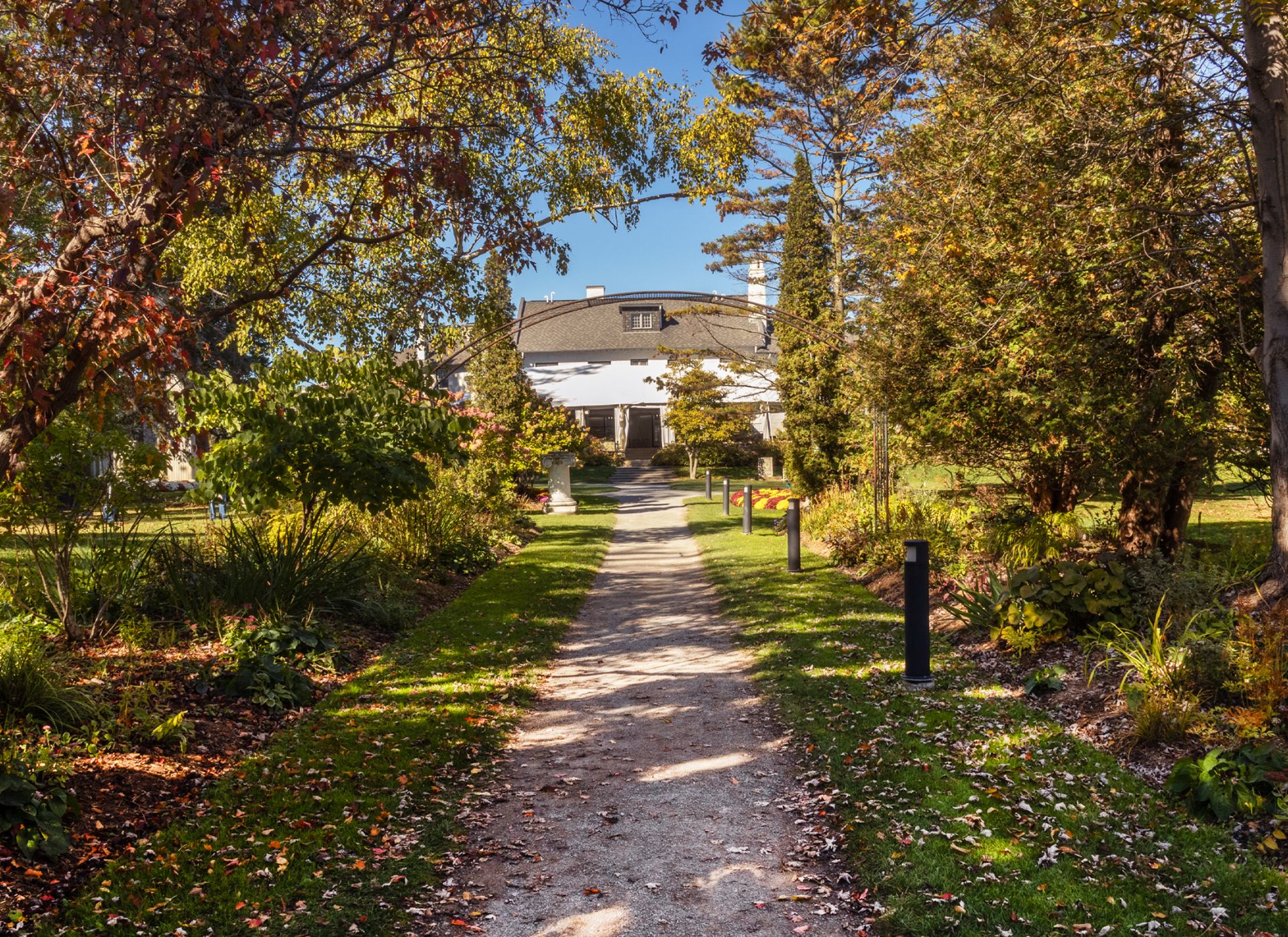 Dirt pathway surrounded by lush vegetation leading to a stucco heritage building.