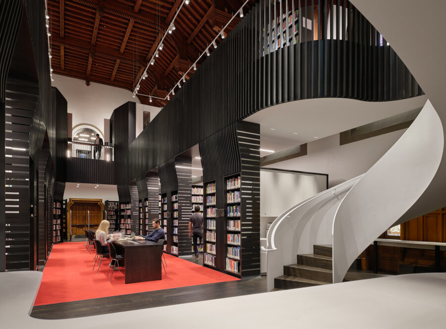 Main floor view of the library at University College, showing the second floor balcony and book stacks. 