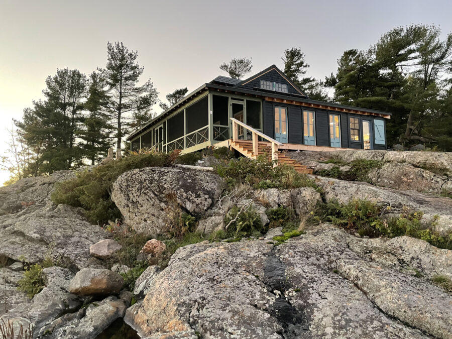 Barronsbrae visible atop the rocky crag and nestled among pines. 