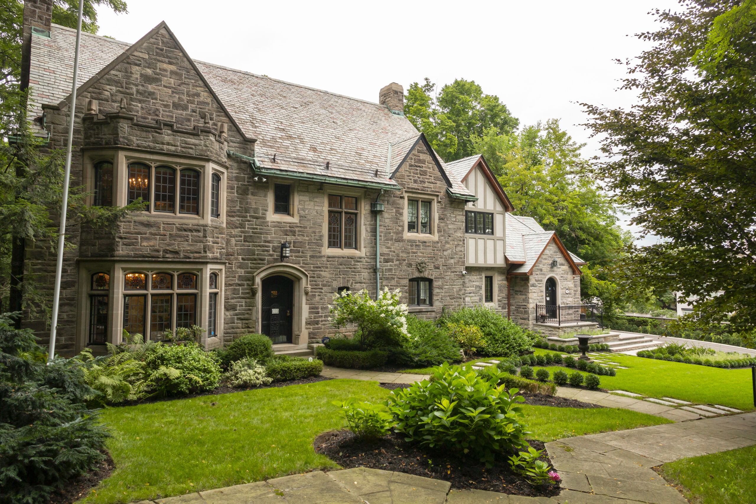 photo of a large stone house taken from an angle, surrounded by trees