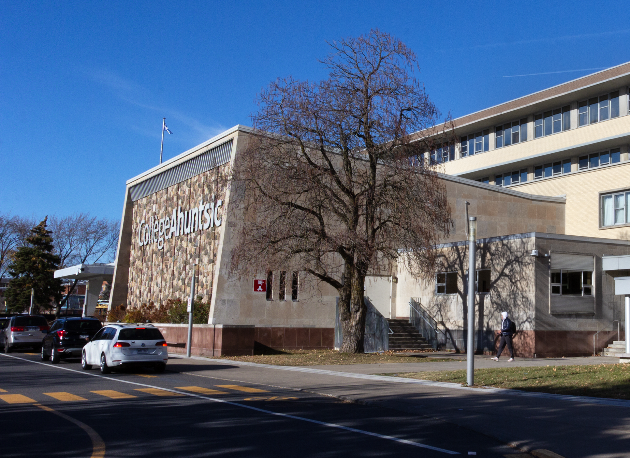 Exterior of Collège Ahuntsic, a concrete building in the background with trees and streets in the foreground.