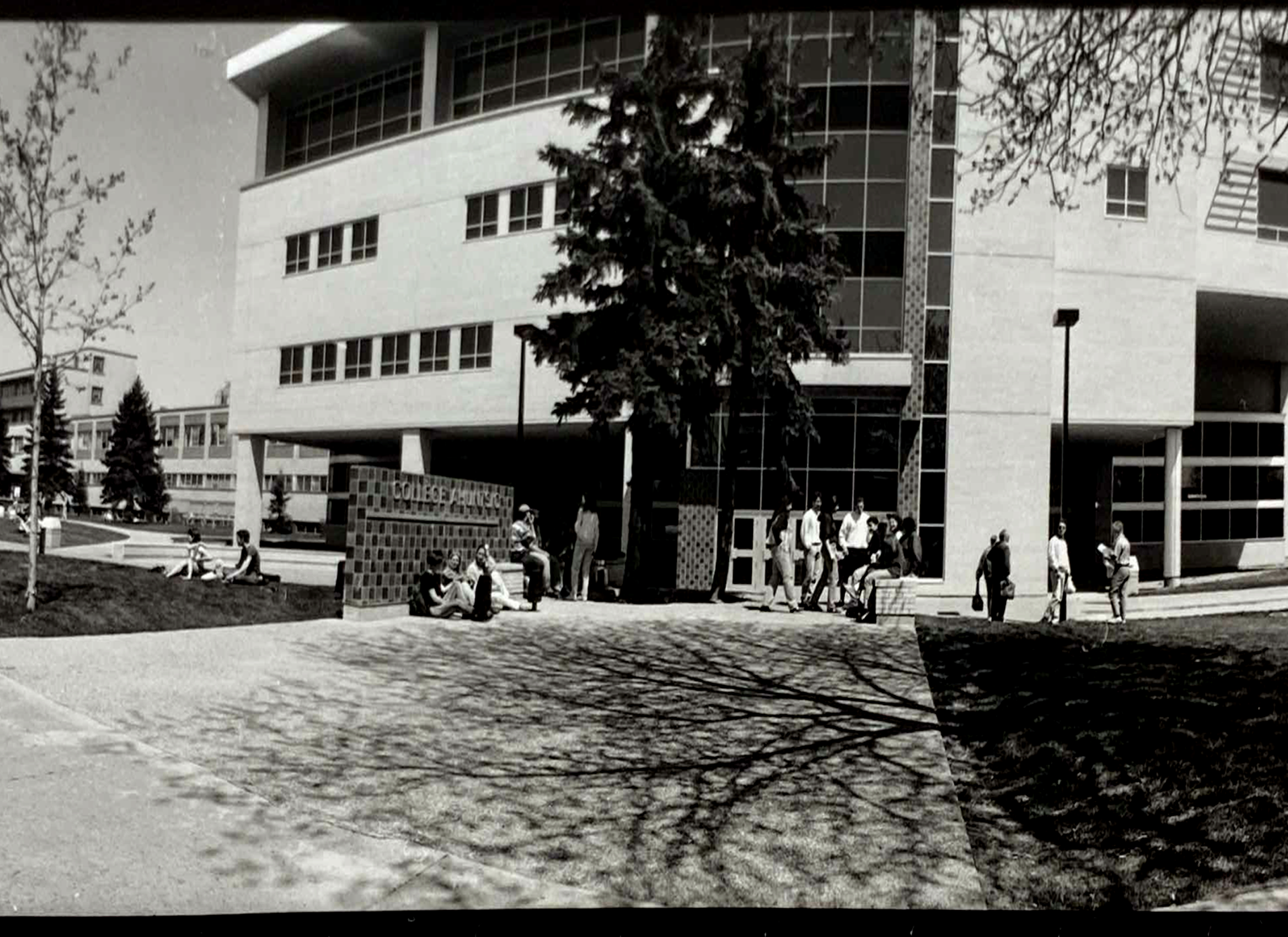 Group of people standing outside Collège Ahuntsic, a concrete modernist building.