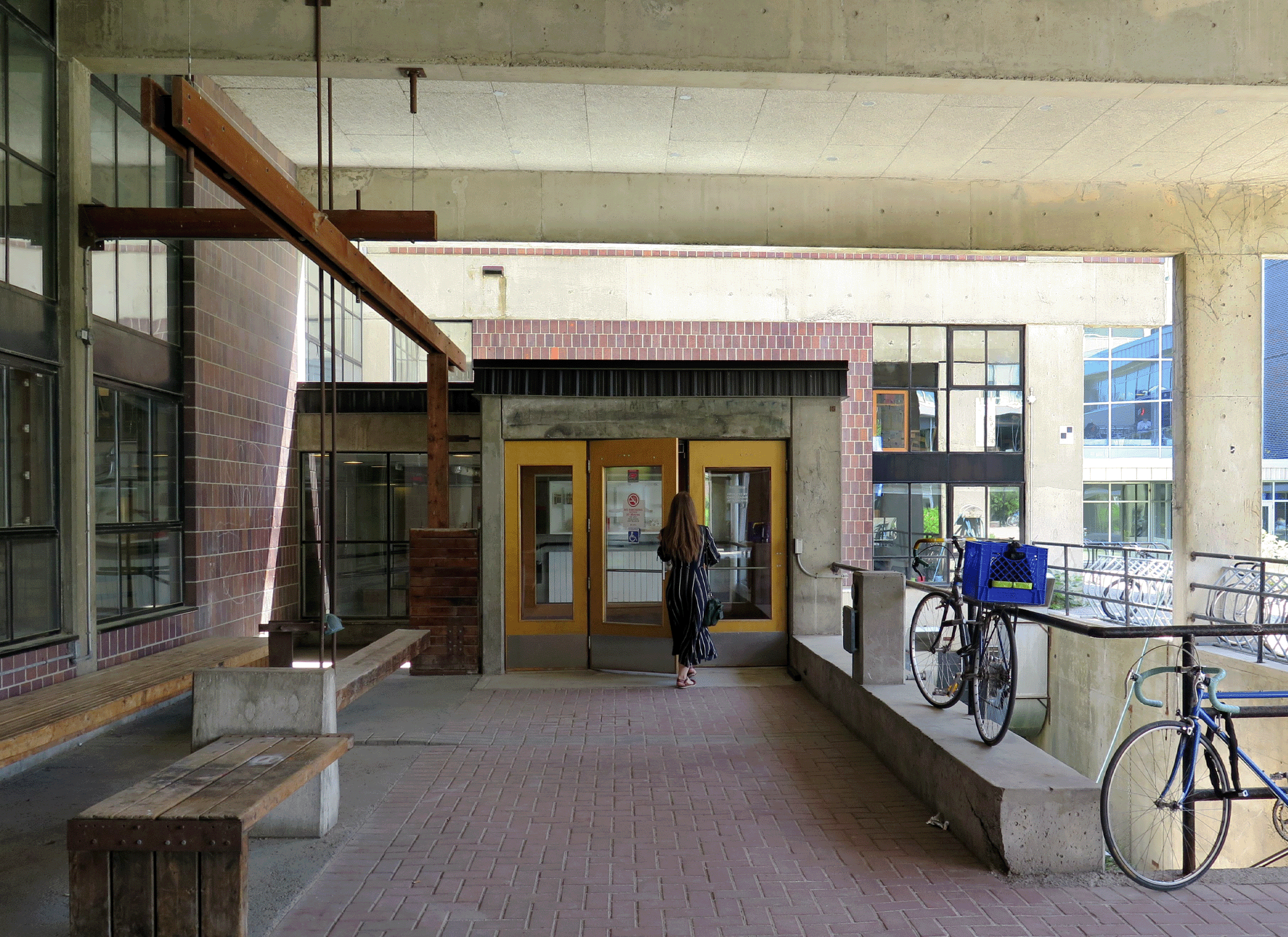 Entryway of Carleton Architecture School with bikes, benches, concrete ceiling and brick floor.