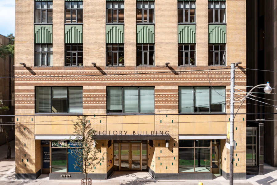 Elevation of 80 Richmond Street with beige and brown decorative brick, copper window sills, and sign.