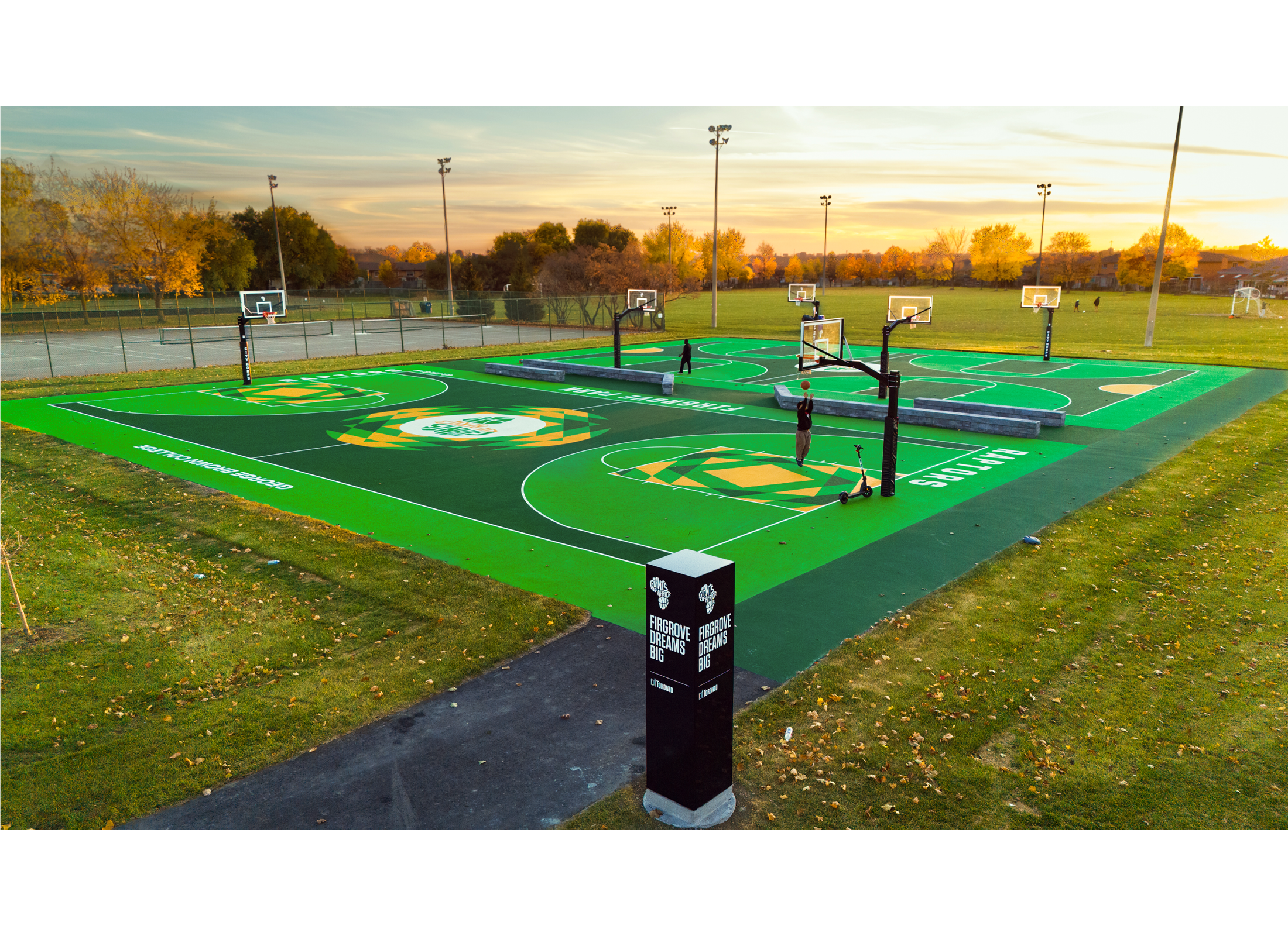 Green and yellow patterned basketball courts with fields and tennis courts in the background.