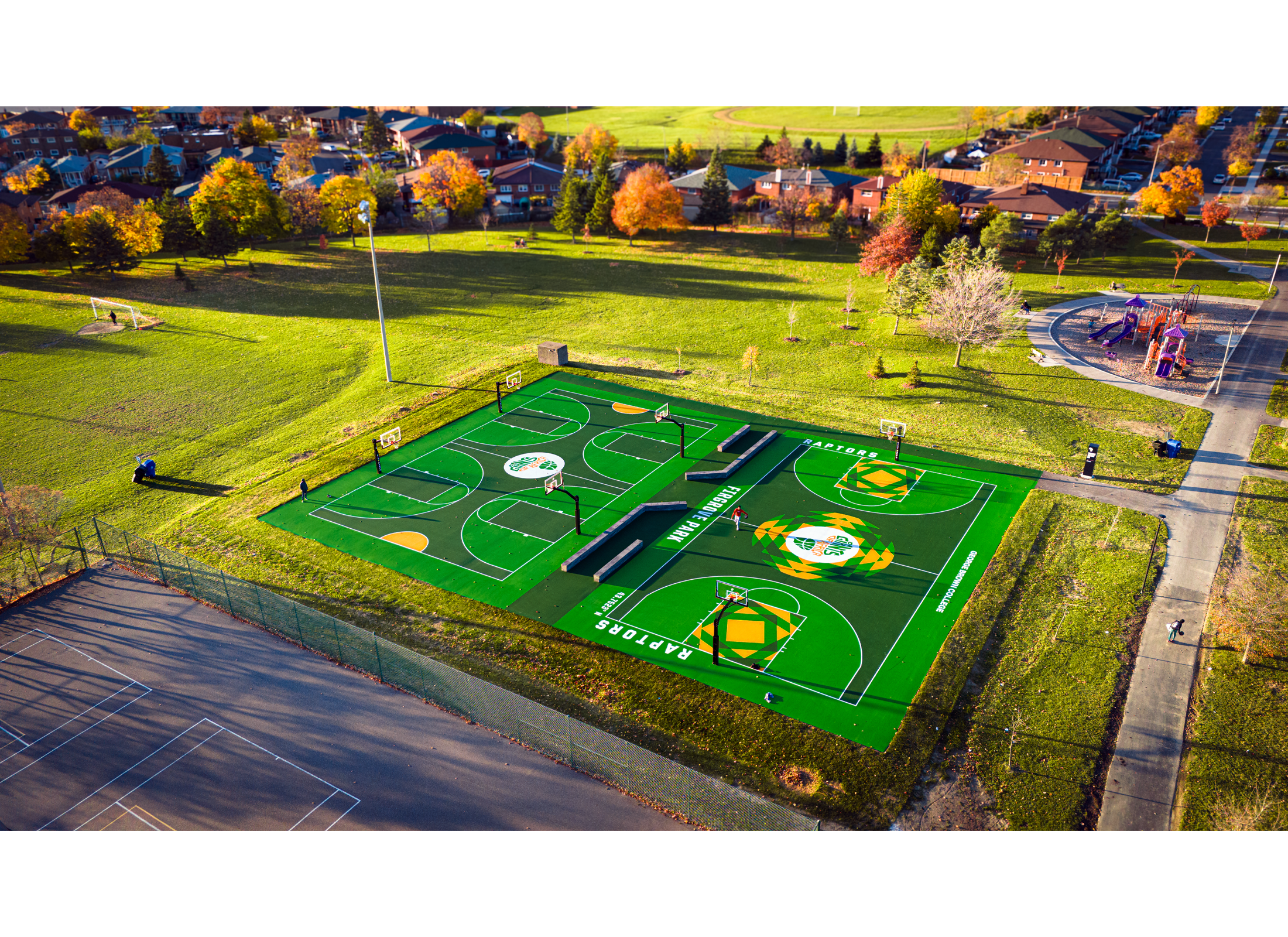Green and yellow patterned basketball courts with fields and tennis courts in the background.