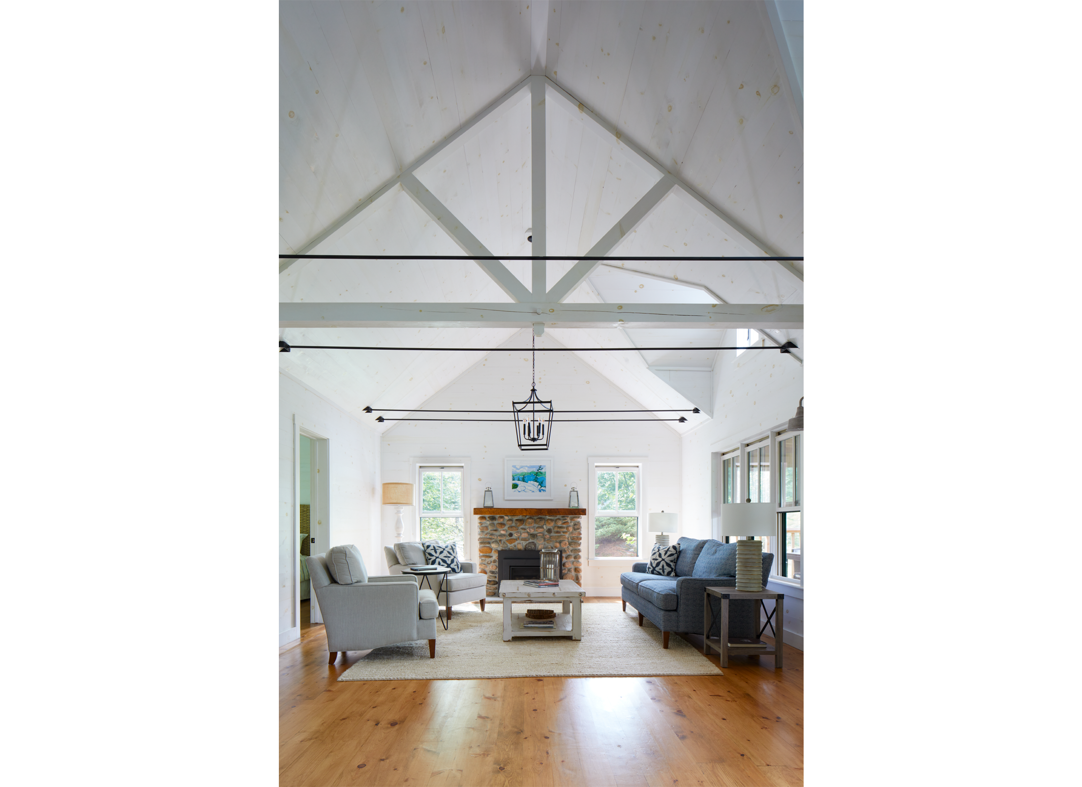 Interior view of Ballentine Pinewood cottage with white vaulted ceilings, stone fireplace, in a living room.