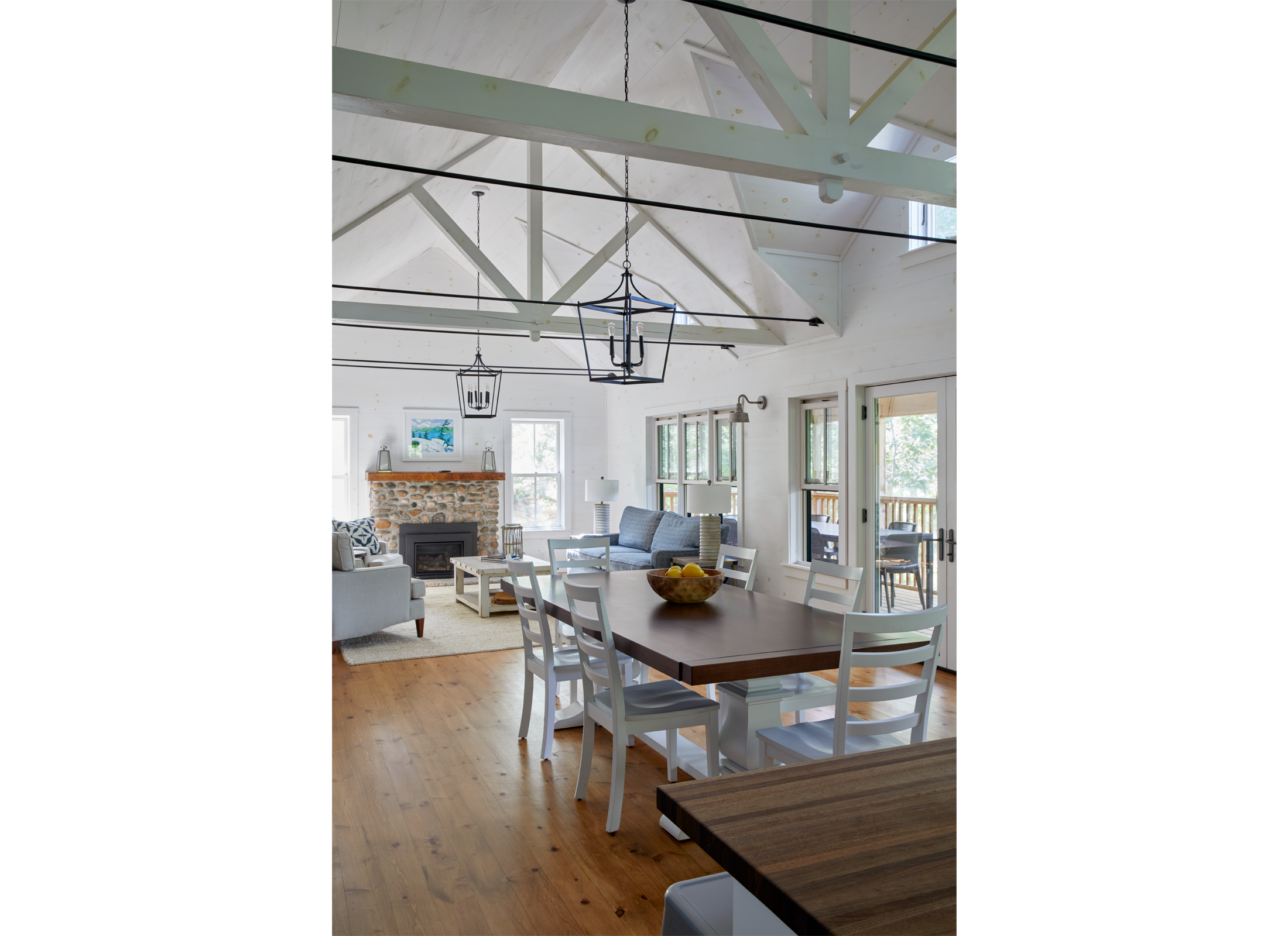 Interior view of Ballentine Pinewood cottage with white vaulted ceilings, stone fireplace, living room, and dining room.