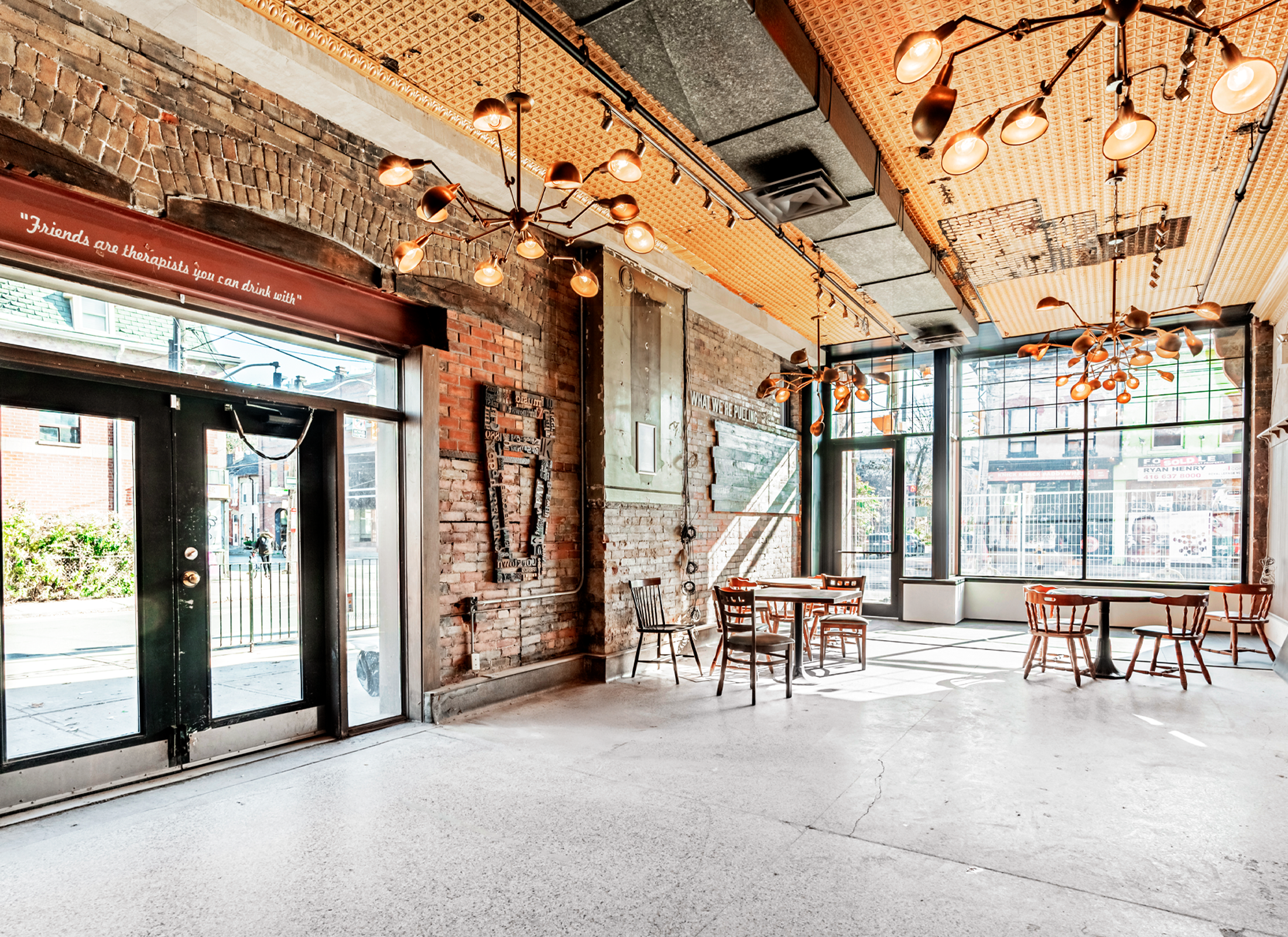 Inside a restaurant with a brick wall, tall glass windows, and seating.