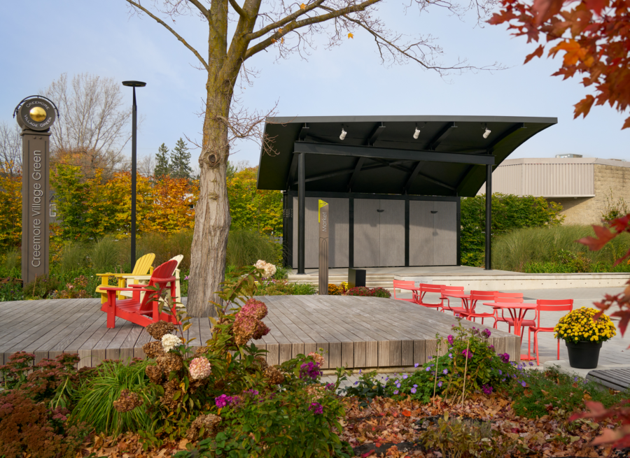 Pavilion with rounded roof surrounding by lush landscape, and red seating.