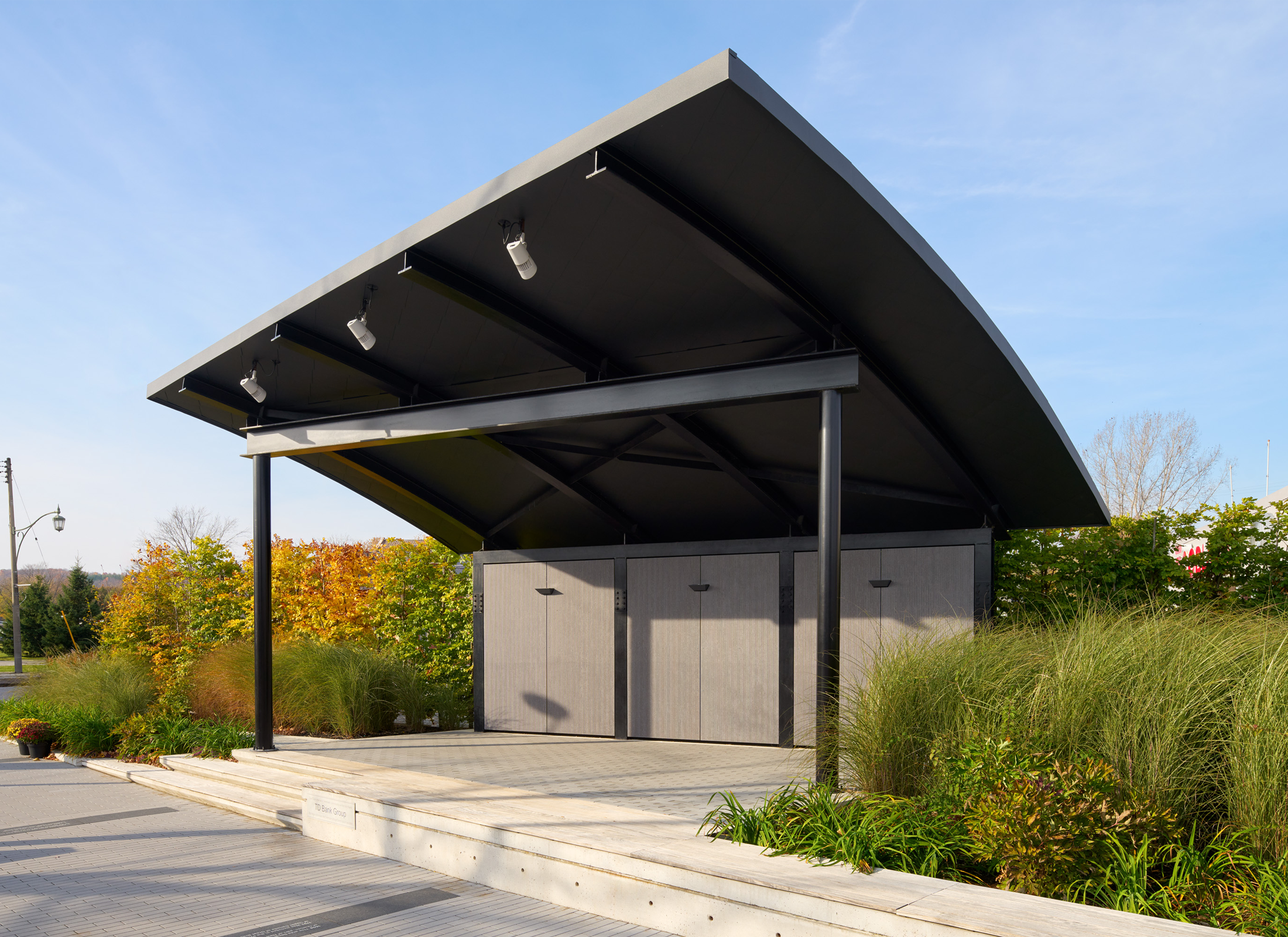 Pavilion with rounded roof surrounding by lush landscape.