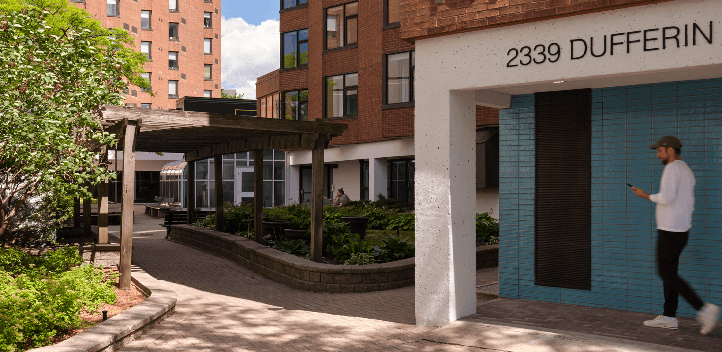 Facade of 2339 Dufferin, with person walking and flowerbeds in the foreground.