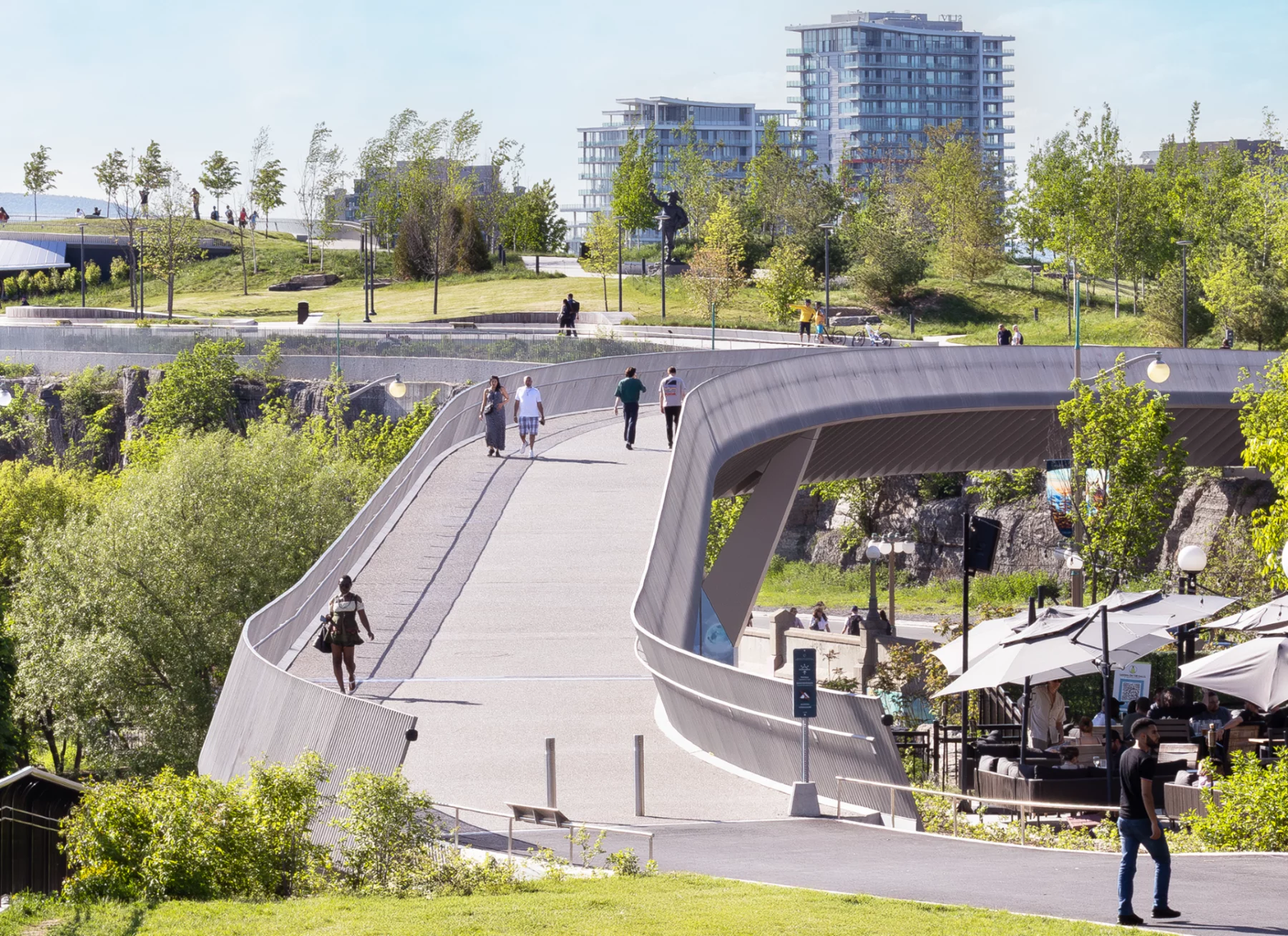 People walking on the Kiweki Point Pedestrian Bridge with surrounding landscape
