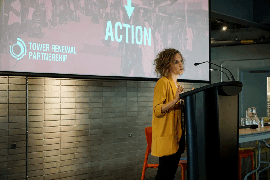 Ya'el Santopinto at a podium speaking to people attending the Tower Renewal Action Forum