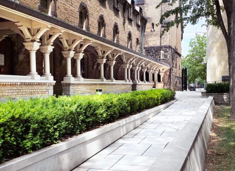 Exterior image of a stone walkway, covered portico and heritage building.