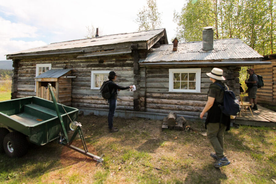Victoria Angel pointing towards an old log cabin in Forty Mile Yukon