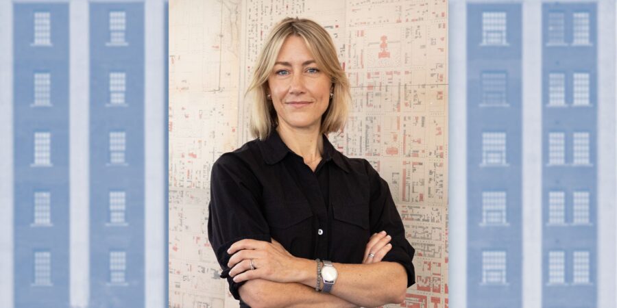 Samantha Irvine standing with her arms crossed in front of an old map