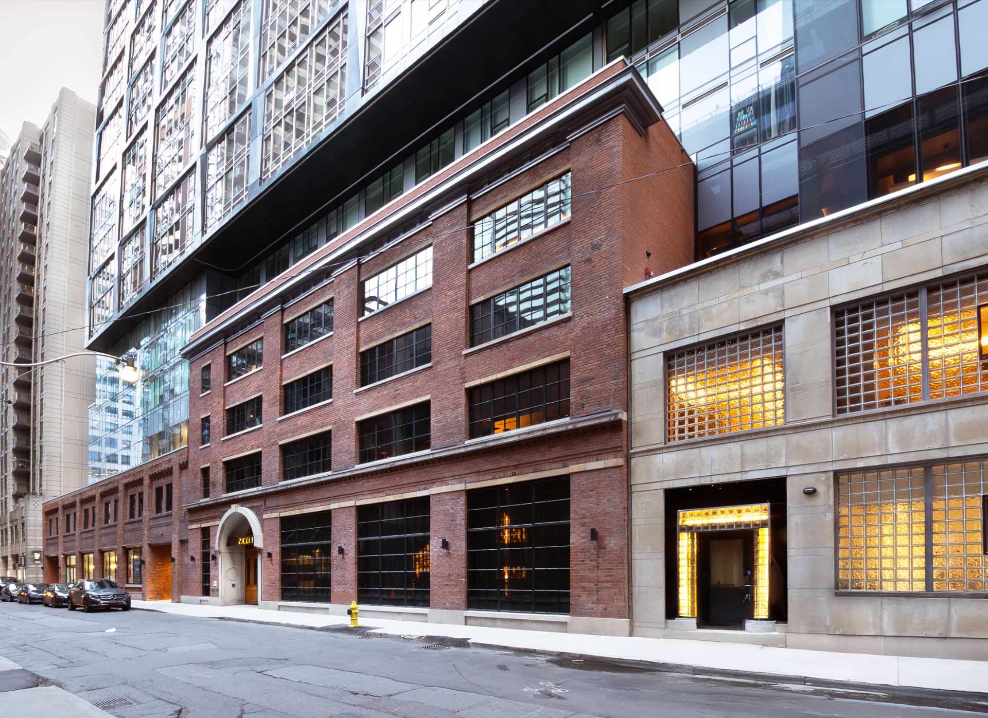 Mid-rise heritage brick building base with a large glass tower on top.