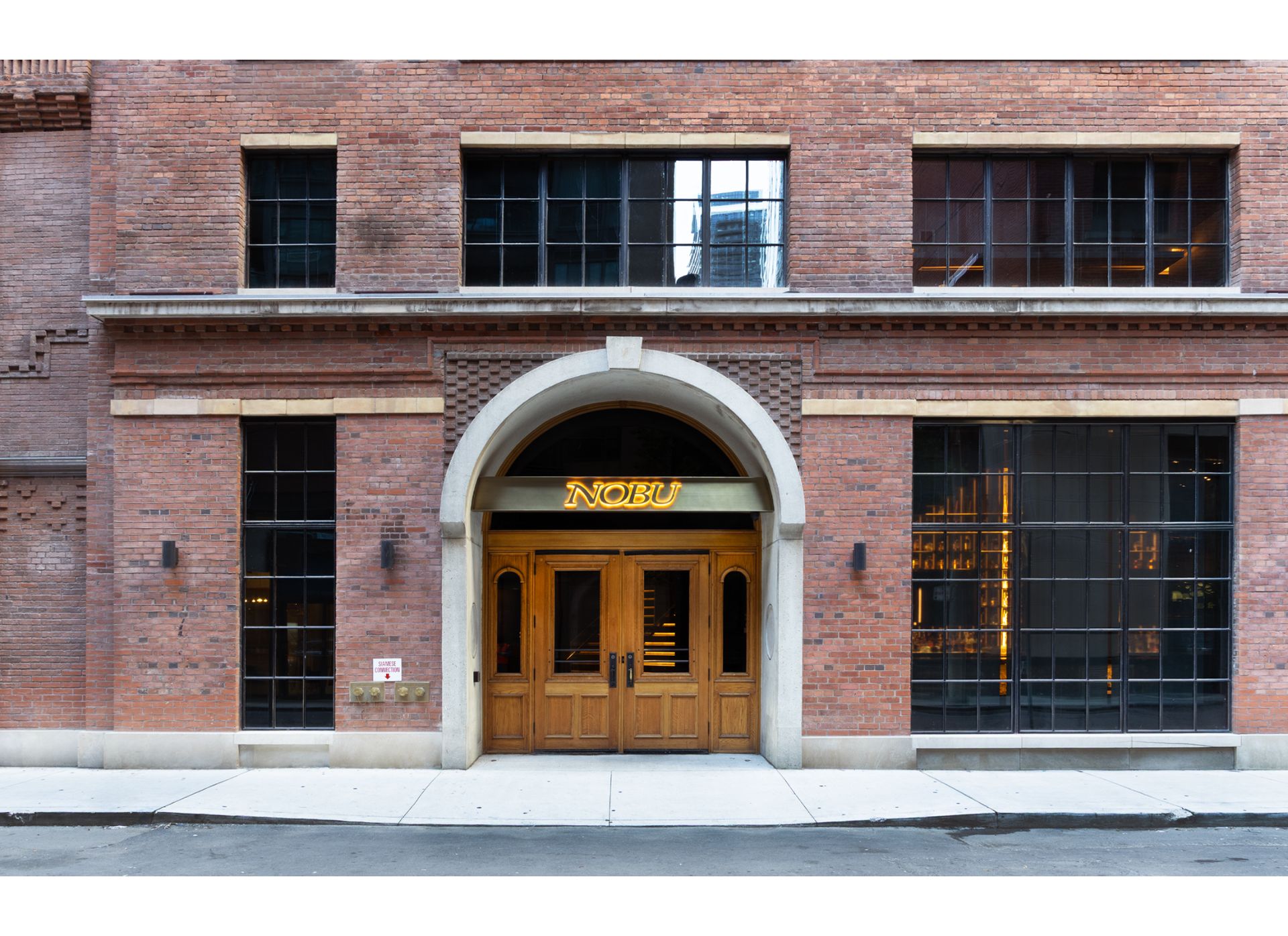 Nobu restaurant entrance, a brick heritage building with grand arched entrance and wooden doors.