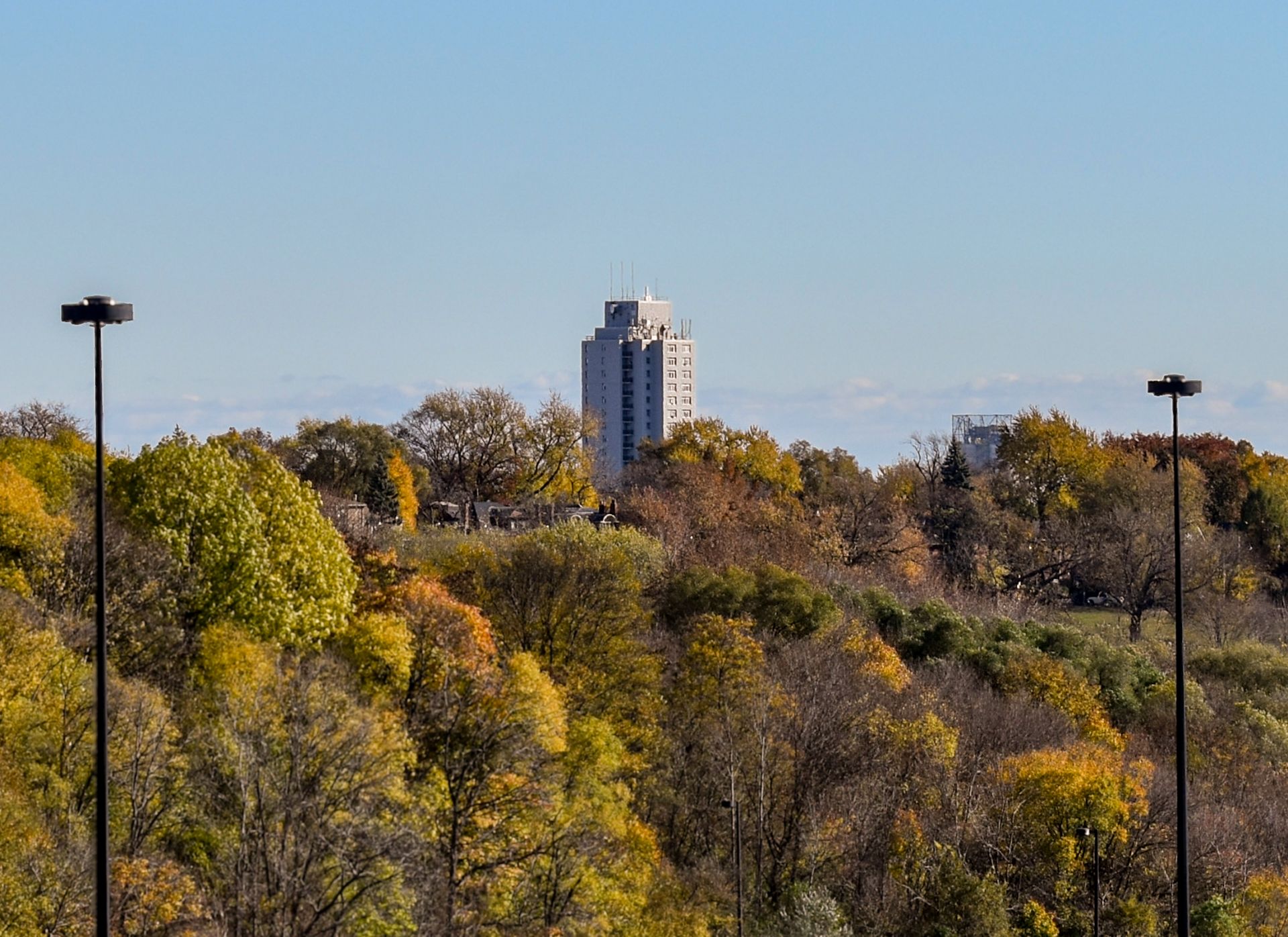 Existing image of 444 Logan tower amidst lush tree landscape.