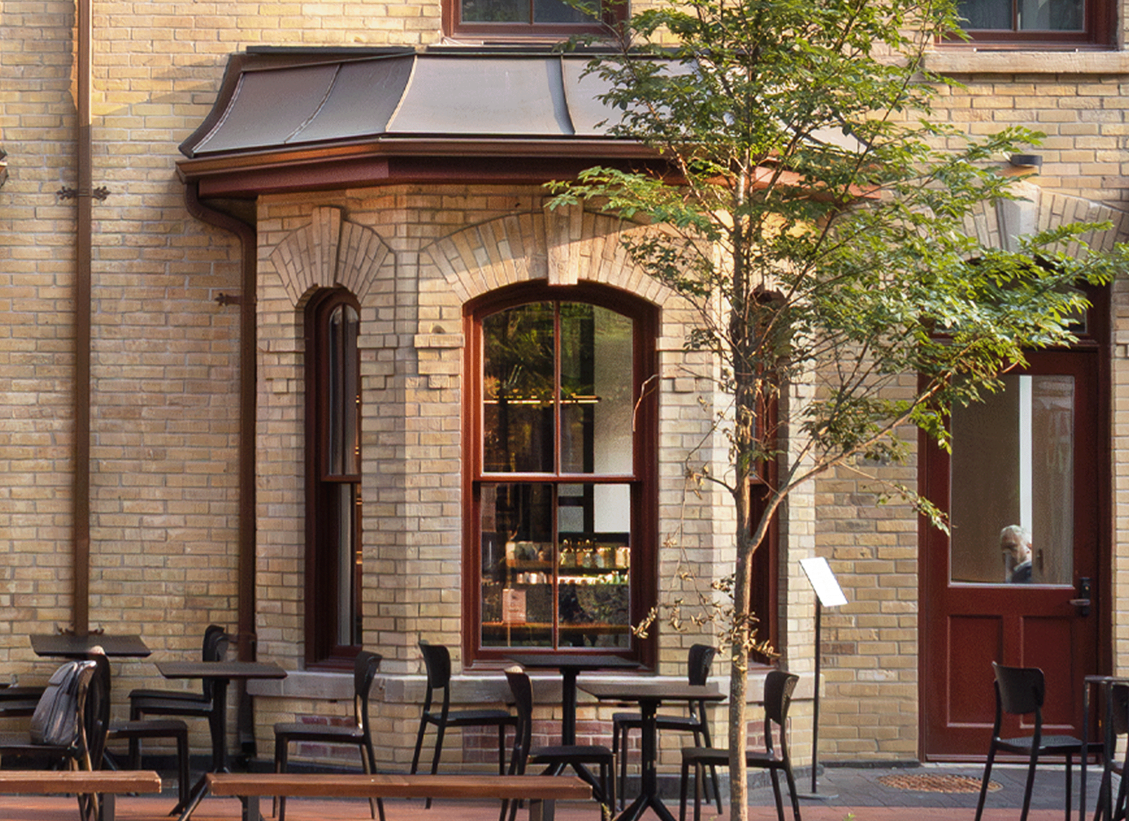 Exterior brick facade of the Charles Levey House with arched windows and outdoor seating at street level.